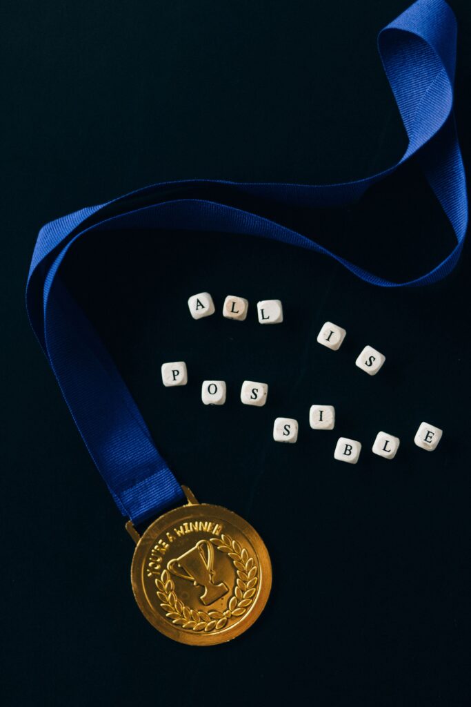 A gold medal with a blue ribbon and 'All is Possible' text on a dark background.